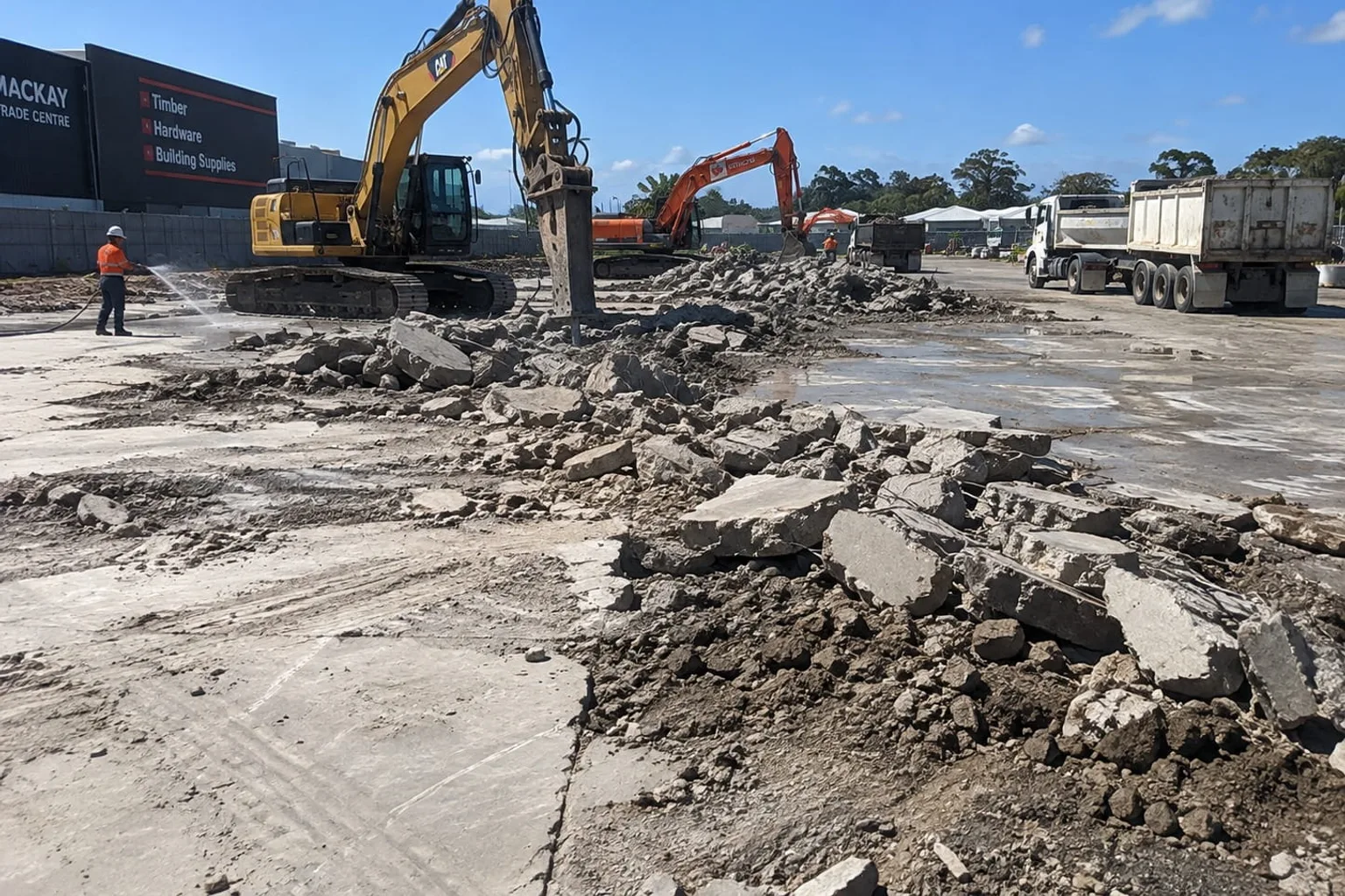 Excavator breaking up a concrete hardstand for removal at a Mackay trade centre